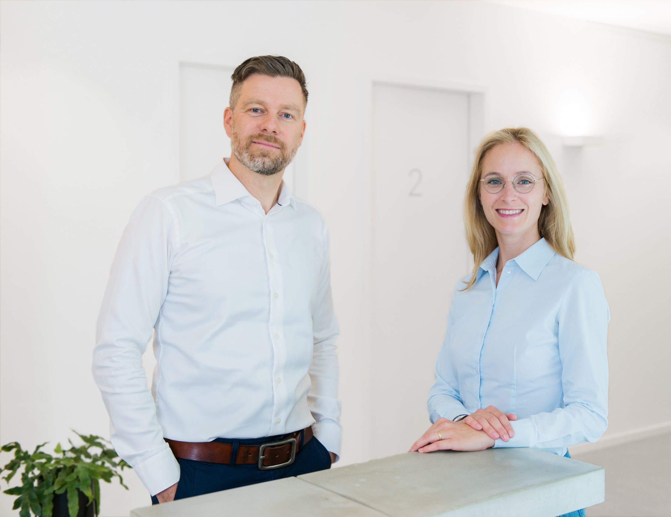 Copyright-Tilman-Vogler-Praxis-Finke+Frantzen-12 Herr Dr. Frantzen und Frau Dr. Finke stehend an einem Thresen mit Blickrichtung zur Kamera